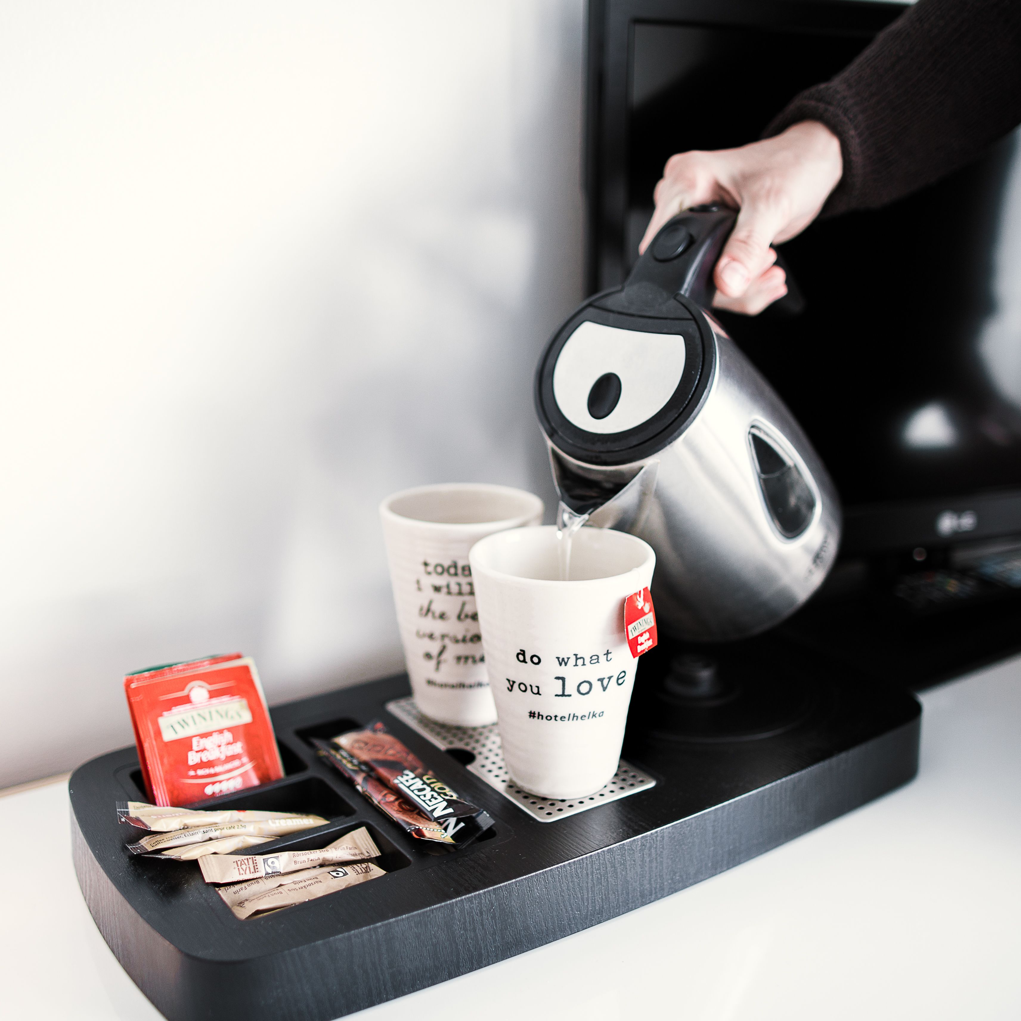 Une machine à café verse du café dans deux tasses posées sur un plateau, à côté d’aliments destinés au petit-déjeuner.