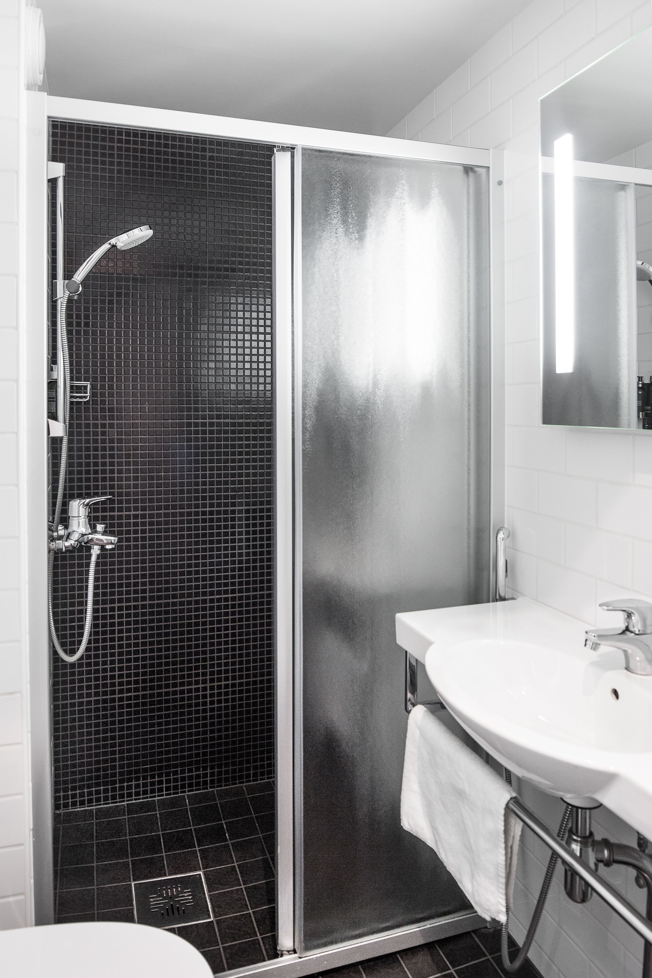 A modern bathroom with a glass-enclosed shower, a white sink, and a mirror above the sink.