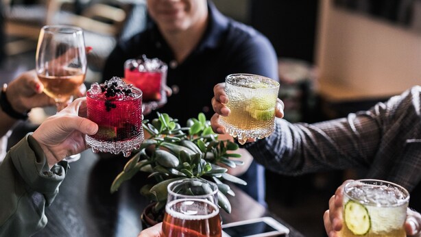A group of people at a bar holding drinks. - Hotel Helka (Helsinki)