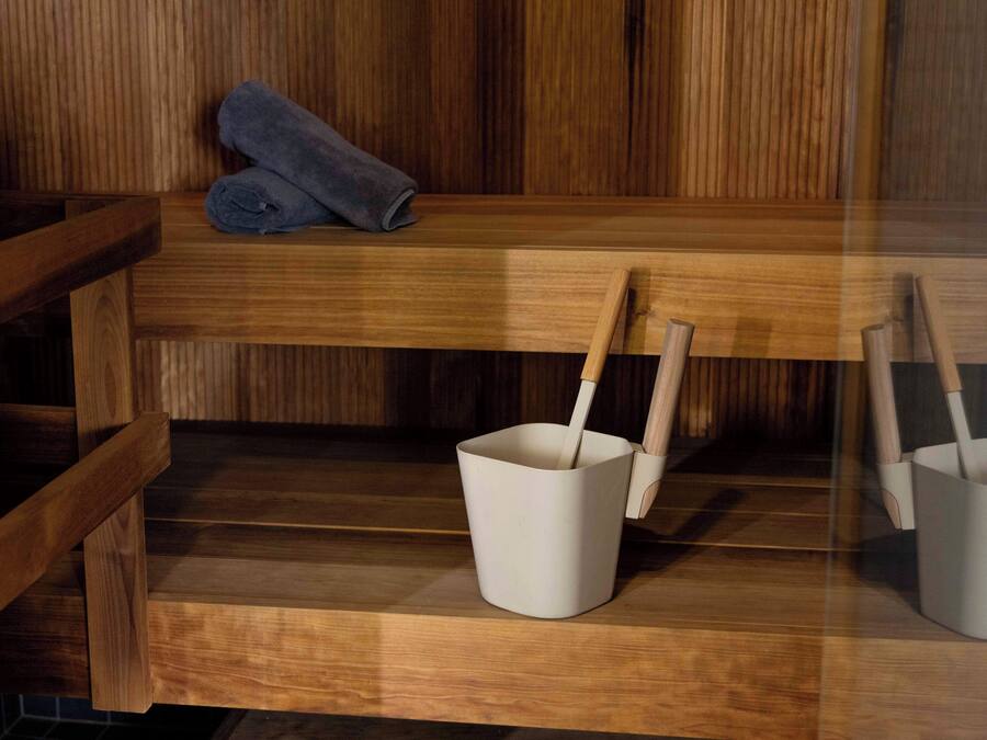 A wooden bench with a rolled towel and two white buckets with wooden handles.