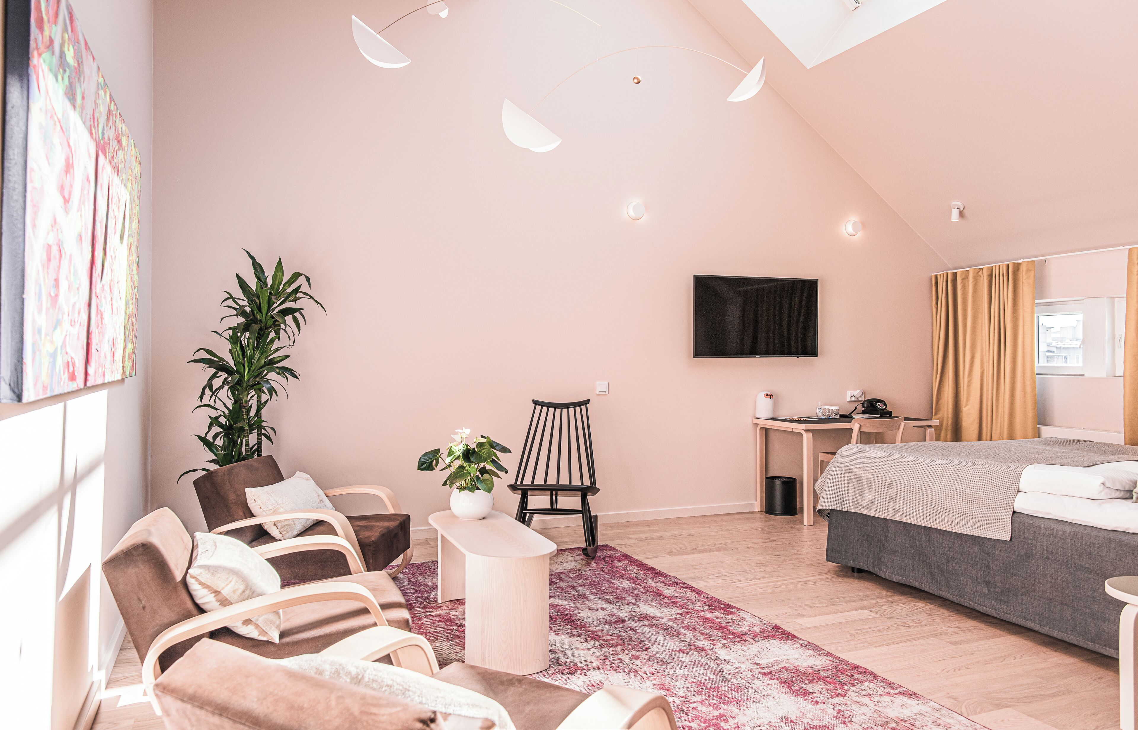 A modern bedroom with a bed, a desk, a chair, and a large potted plant.