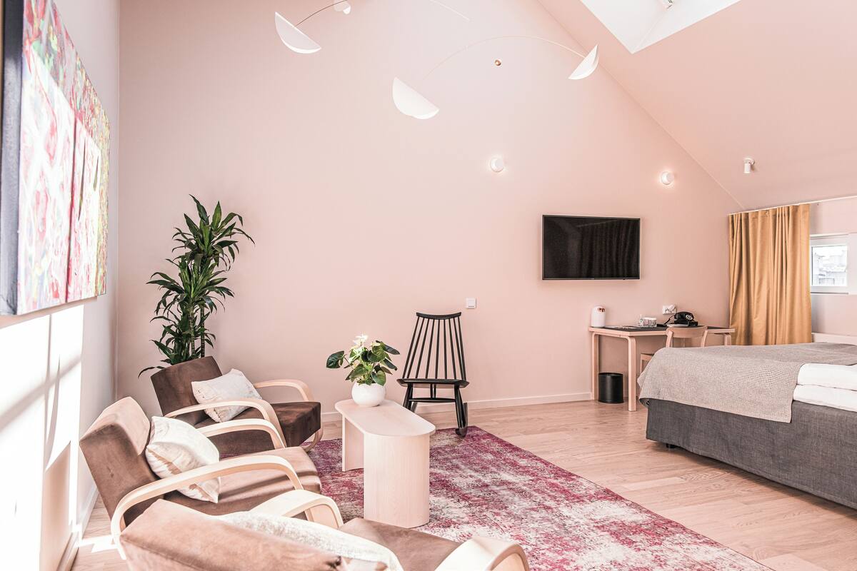 Un dormitorio moderno con cama, escritorio, silla y una planta grande en maceta.