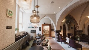 A spacious lobby with a high ceiling, modern lighting fixtures, and a stone fireplace. - Home Hotel Jugend (Helsinki)