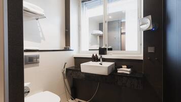 A modern bathroom with a white sink, dark marble countertop, and a large mirror.