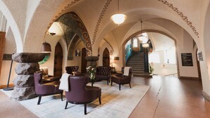 A lobby with arched ceilings, stone pillars, and leather furniture. - Home Hotel Jugend (Helsinki)