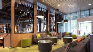 Un hall d’entrée moderne doté d’espaces aménagés avec des sièges, d’un comptoir de réception et de grandes fenêtres.