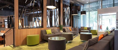 A modern lobby with seating areas, a reception desk, and large windows.