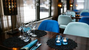 A restaurant interior with a wooden table set for dining, including wine glasses and cutlery. - Hotel Oscar (Varkaus)