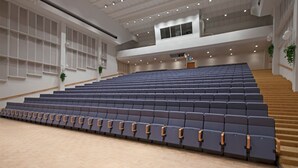 A spacious auditorium with tiered seating, a wooden floor, and a staircase leading to an upper level. - Hotel Oscar (Varkaus)