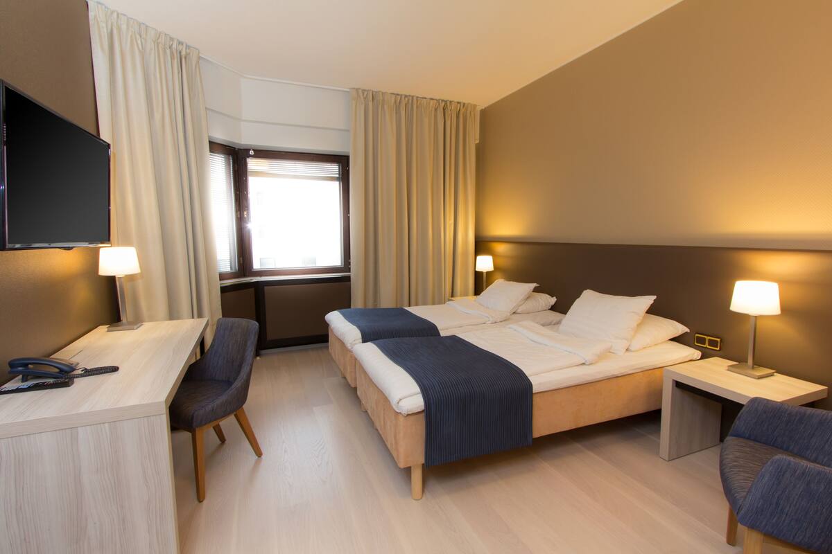 A hotel room with a bed, desk, and chairs.