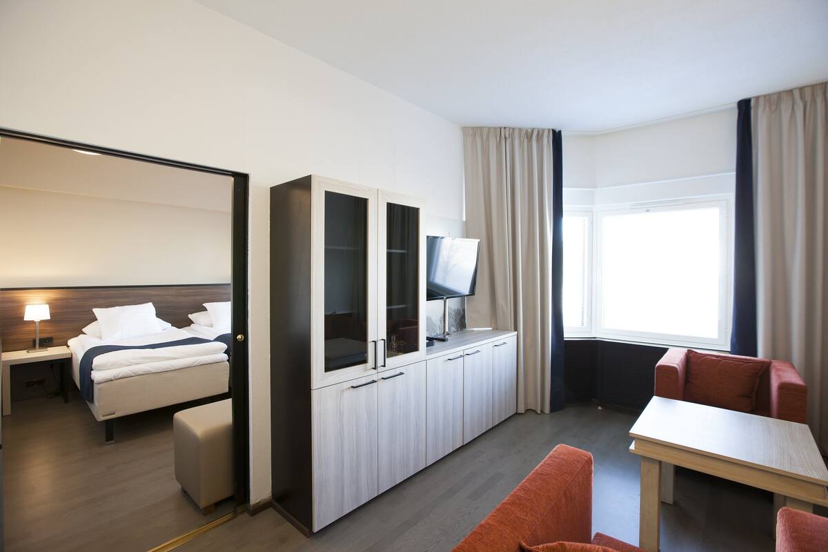 A hotel room with a bed, a desk, a TV, and a window with curtains.