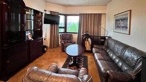A living room with a leather sofa, a coffee table, a TV, and a bookshelf. - Hotel Oscar (Varkaus)