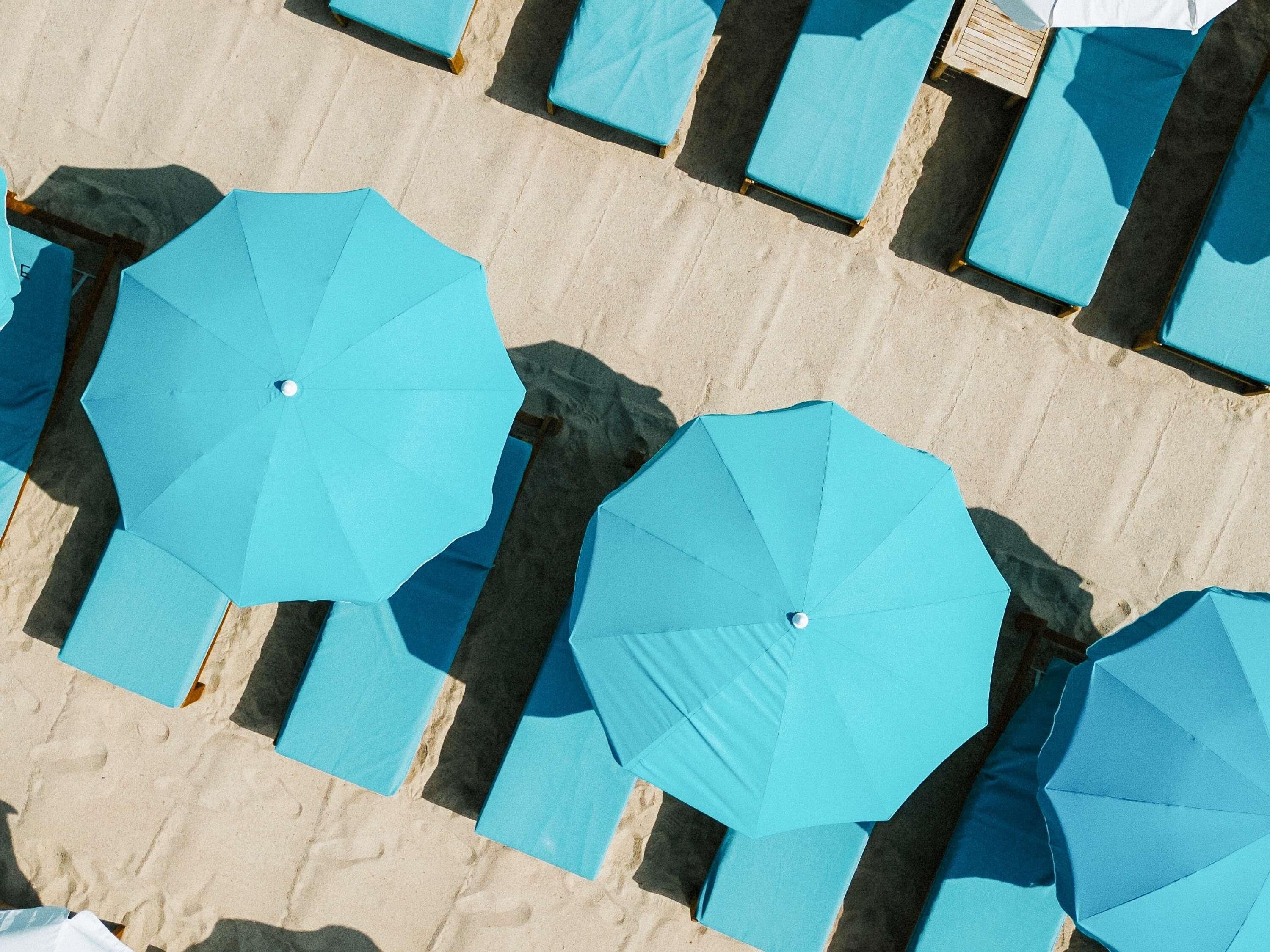 Ein Strand mit mehreren Liegestühlen und Sonnenschirmen.