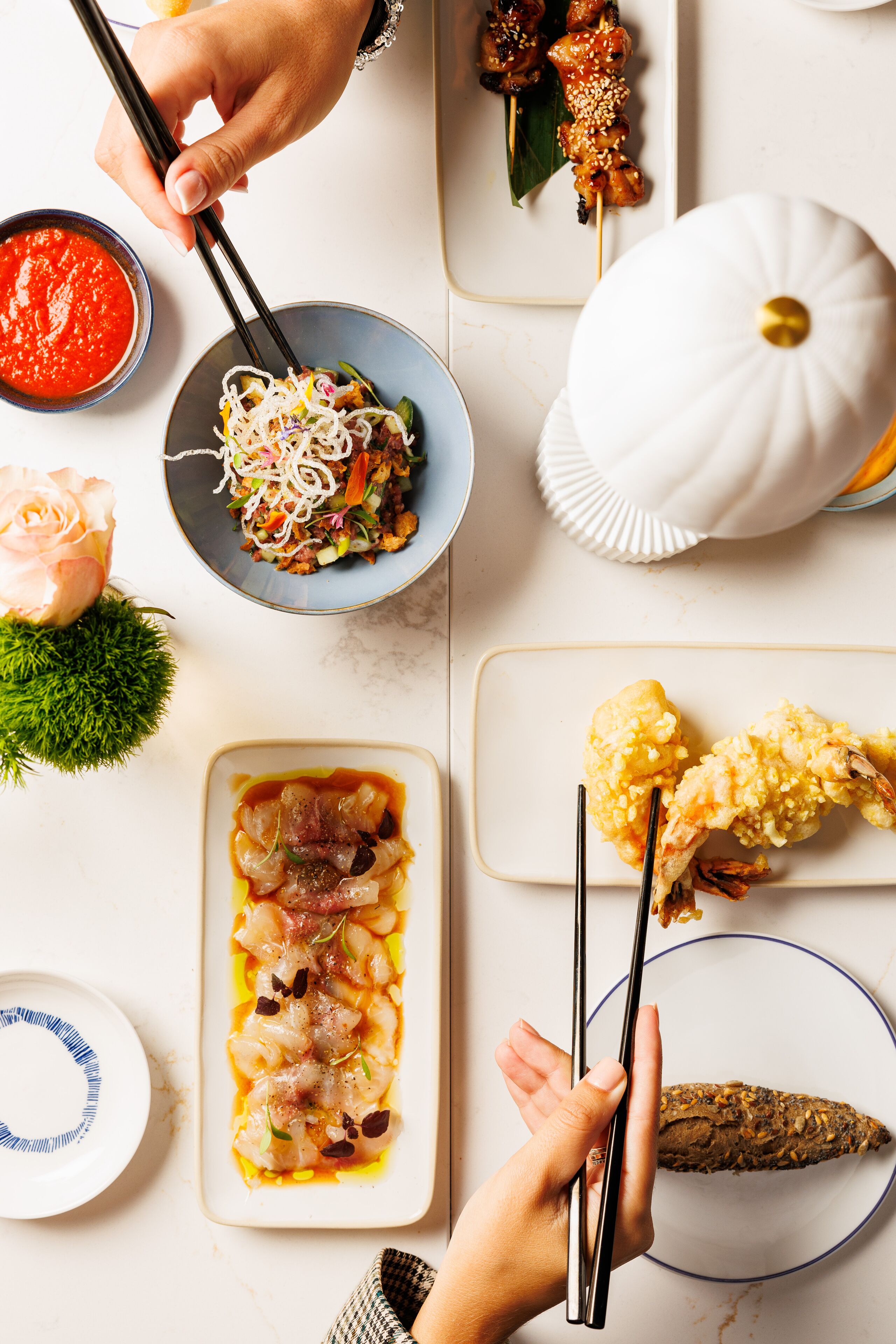 A table with various dishes, including skewers, noodles, and a bowl of soup.