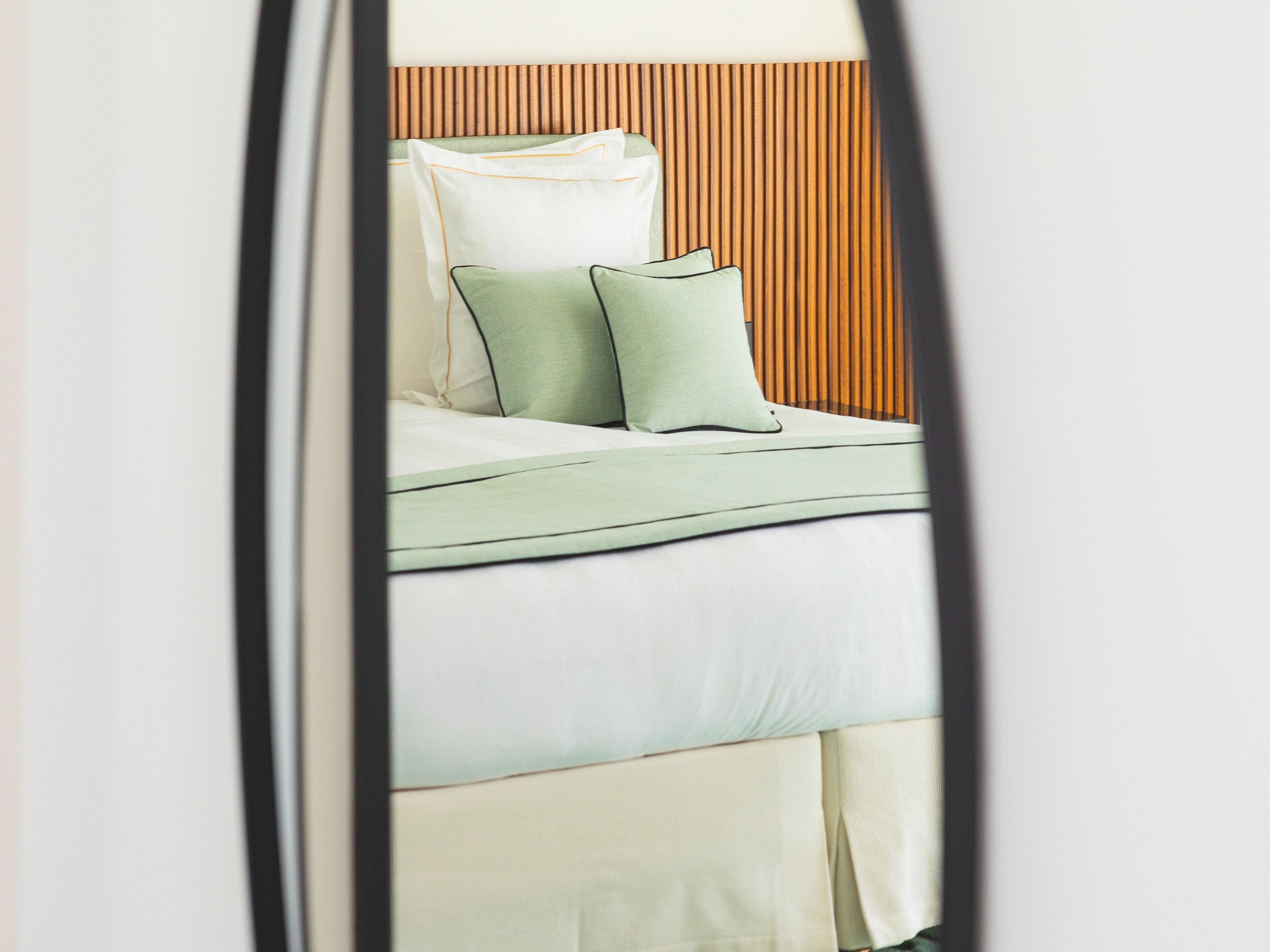 Una cama con cabecera de madera, ropa de cama blanca y dos almohadas.