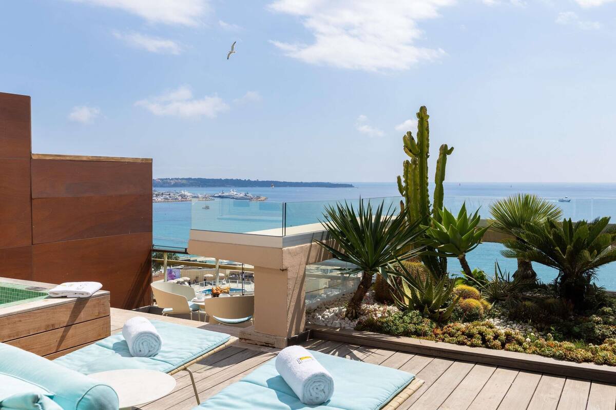 A rooftop terrace with a pool, sun loungers, and a view of the sea.