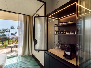 A hotel room with a balcony, a minibar, and a coffee machine.