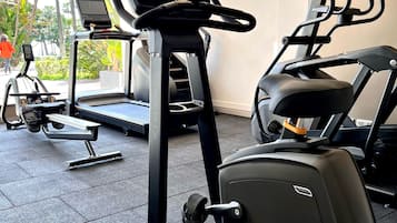 Un gimnasio con bicicletas estáticas, cintas de correr y una máquina de remo.