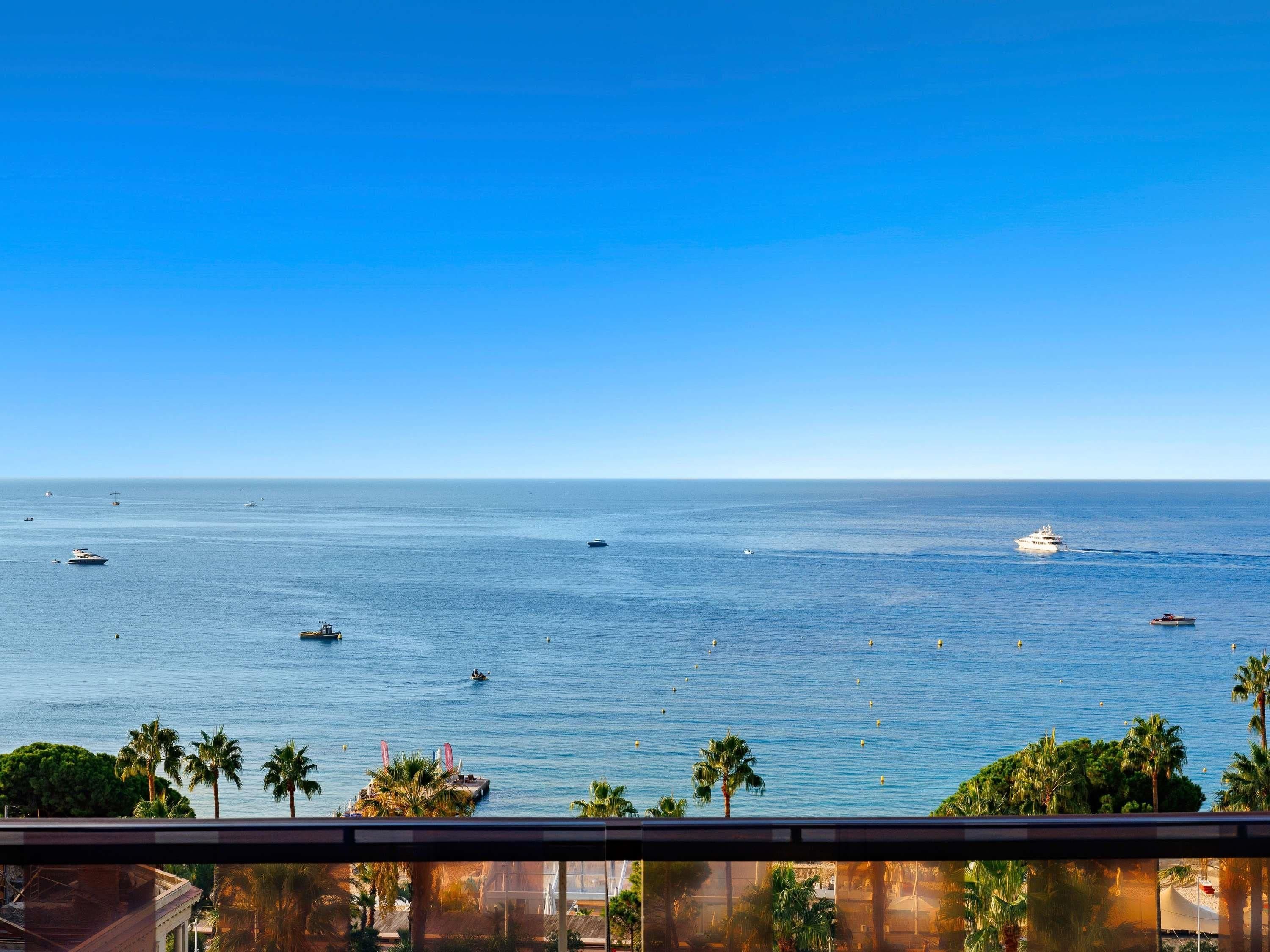 Vista del océano con barcos y palmeras.