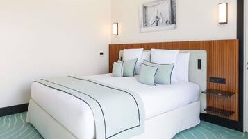 Una habitación de hotel con una cama, cabecera, una obra de arte en la pared y una mesita de noche.