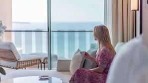 A woman sitting on a balcony chair, holding a cup, with a view of the sea. - Mondrian Cannes (Cannes)