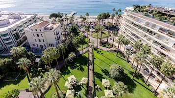 Un hotel con piscina en la azotea, palmeras y vistas al mar.