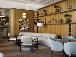 A modern living room with a sofa, chairs, a coffee table, and a wooden wall with shelves holding decorative items.