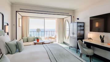 Een hotelkamer met een groot bed, een bureau, een stoel, een kleine tafel en een balkon met uitzicht.