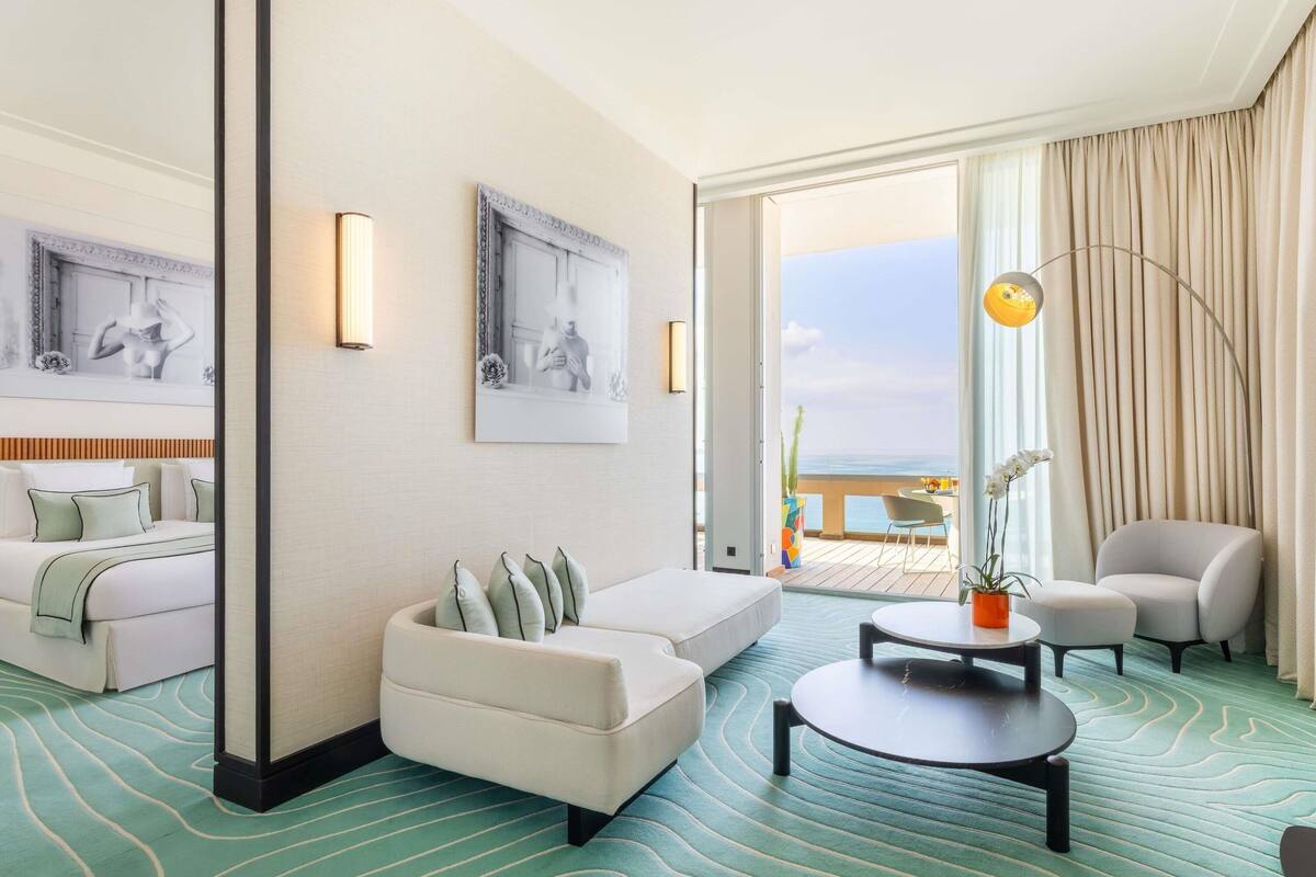 A hotel room with a bed, a sofa, a coffee table, and a view of the ocean.