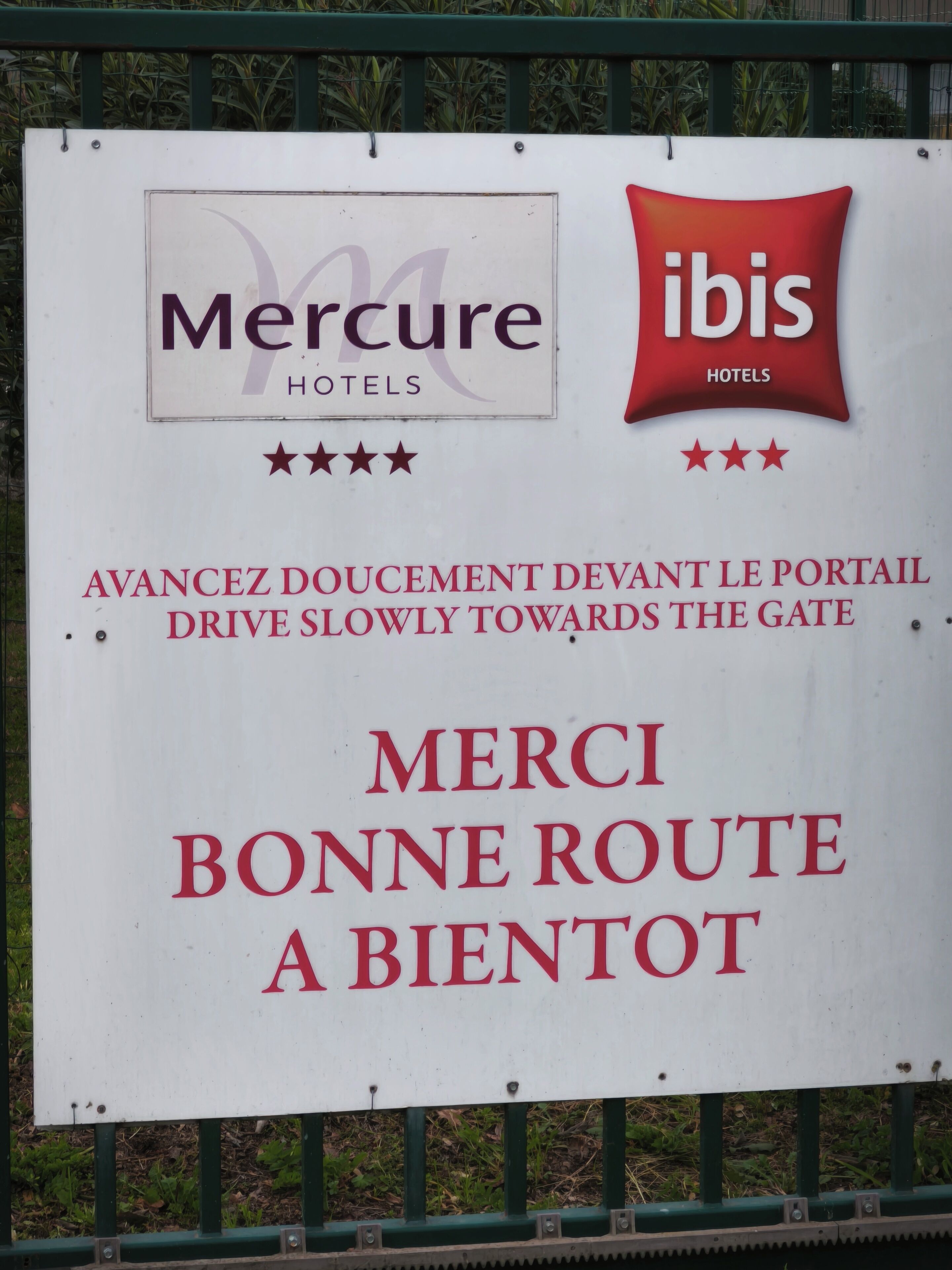 A sign with logos of Mercure and ibis hotels, a directional instruction in French, and a thank you message.