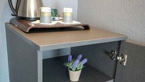 A kitchenette with a coffee maker, a small potted plant, and a mini-fridge containing beverages. - Mercure Cavaillon Hotel (Cavaillon)