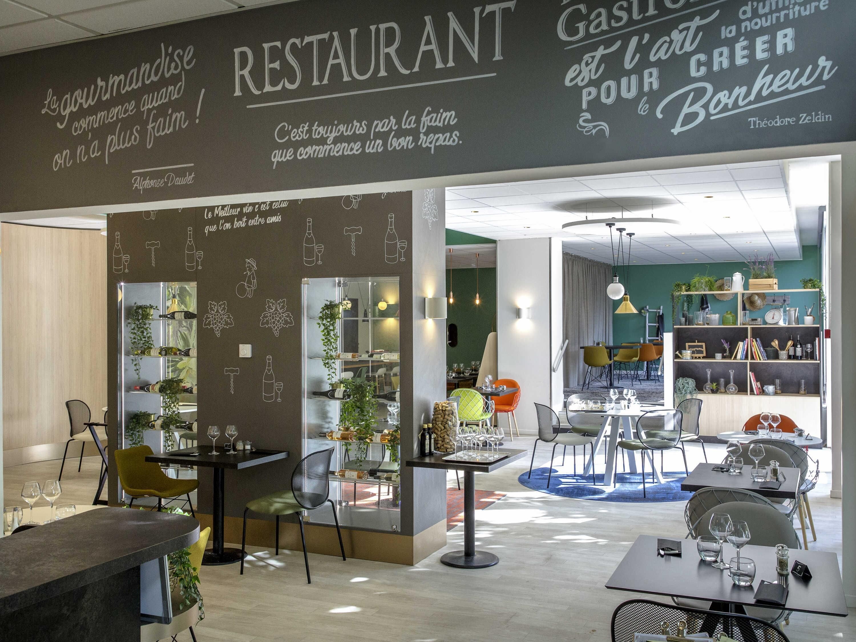 A restaurant interior with a modern design, featuring a bar area, dining tables, and a variety of seating options.