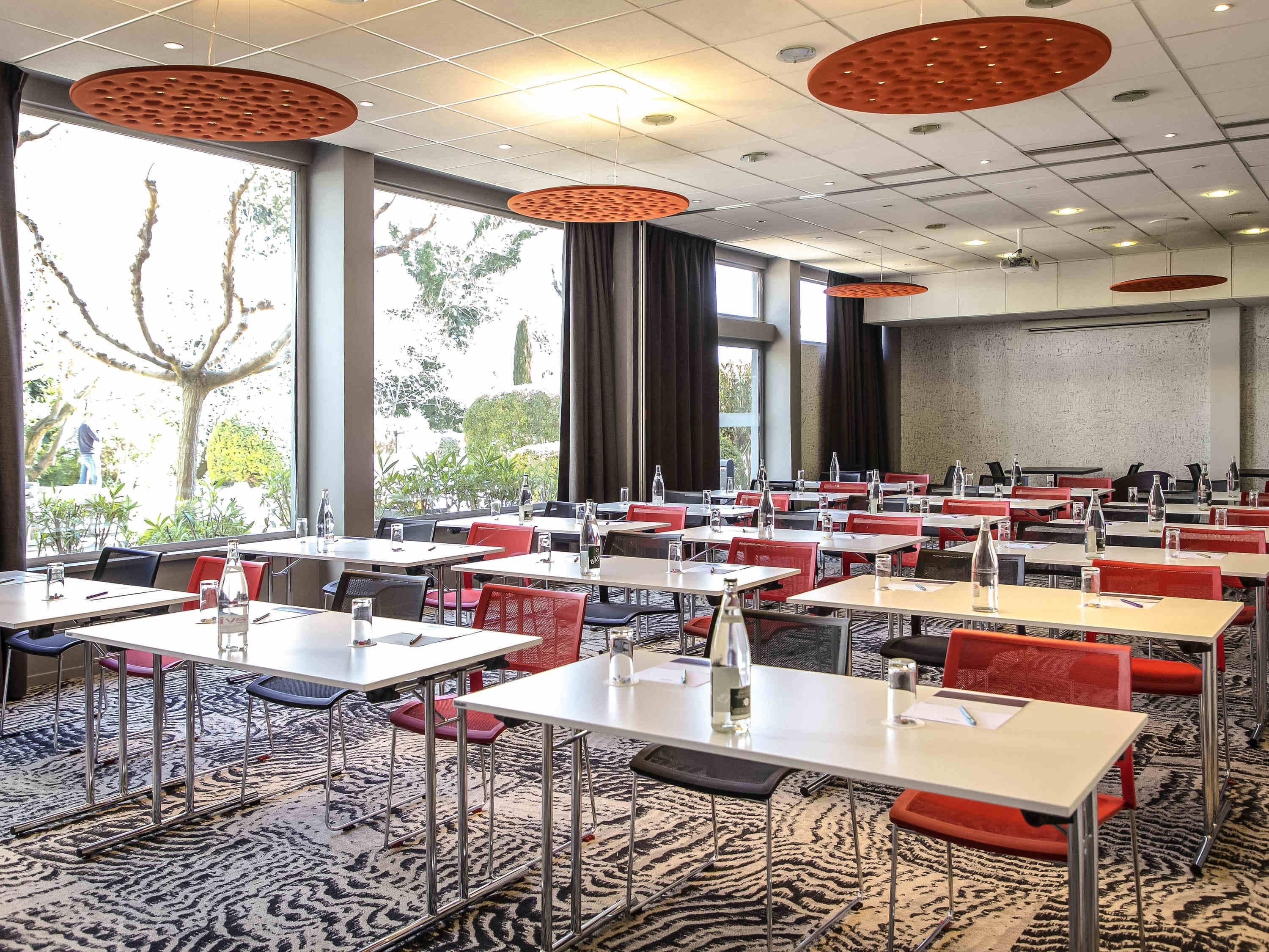 A conference room with tables, chairs, and a projector screen.