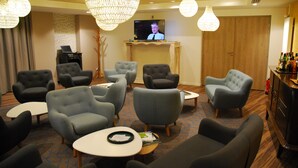 A hotel lounge with multiple seating areas, a television, and a bar.