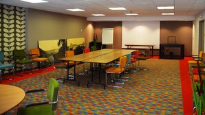 A conference room with a large table, multiple chairs, a projector screen, and a whiteboard.