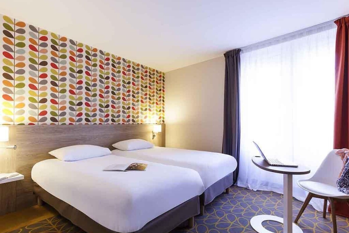 A hotel room with two beds, a desk, and a chair.