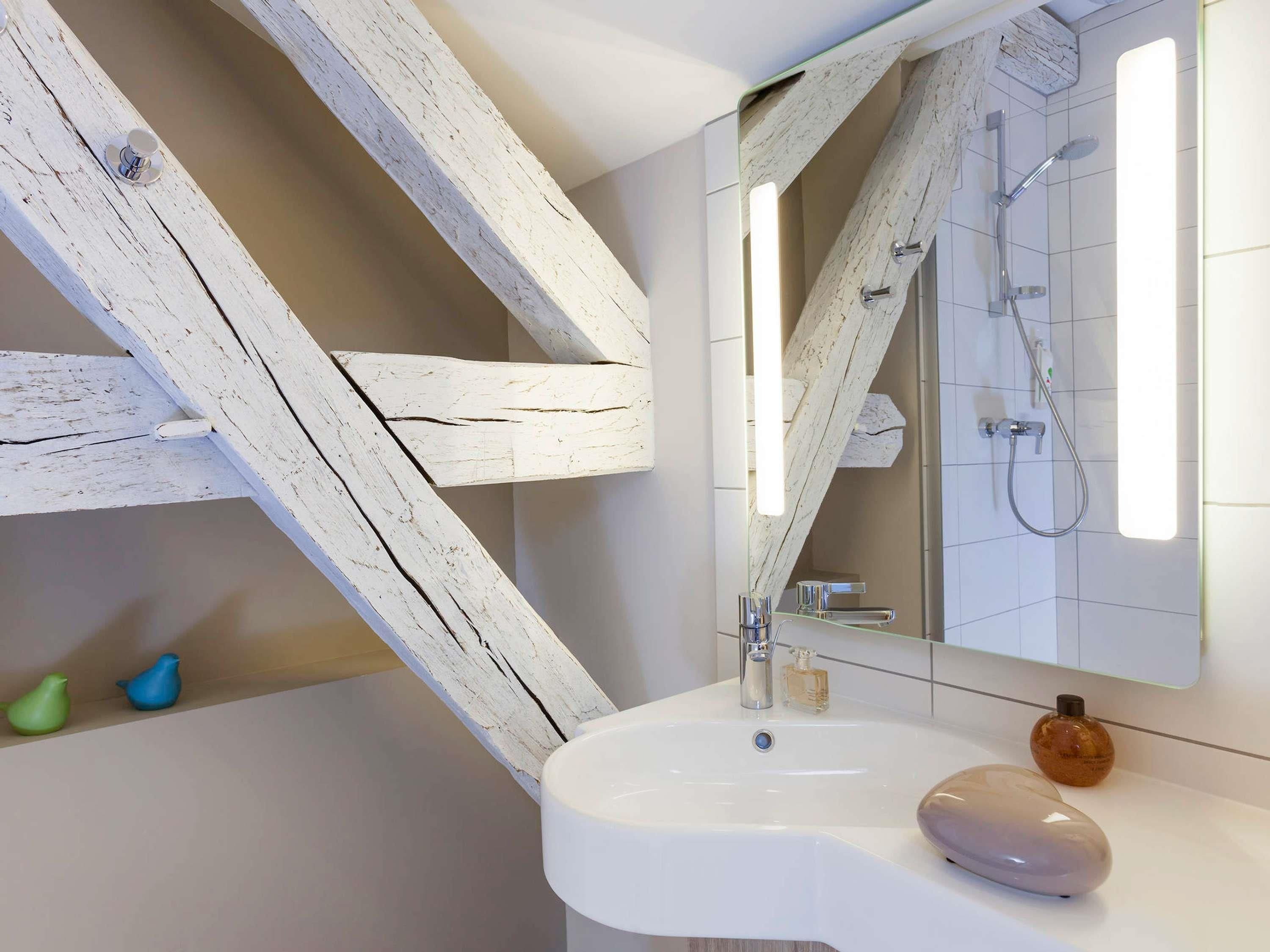 A bathroom with a white sink, a mirror, and a shower.