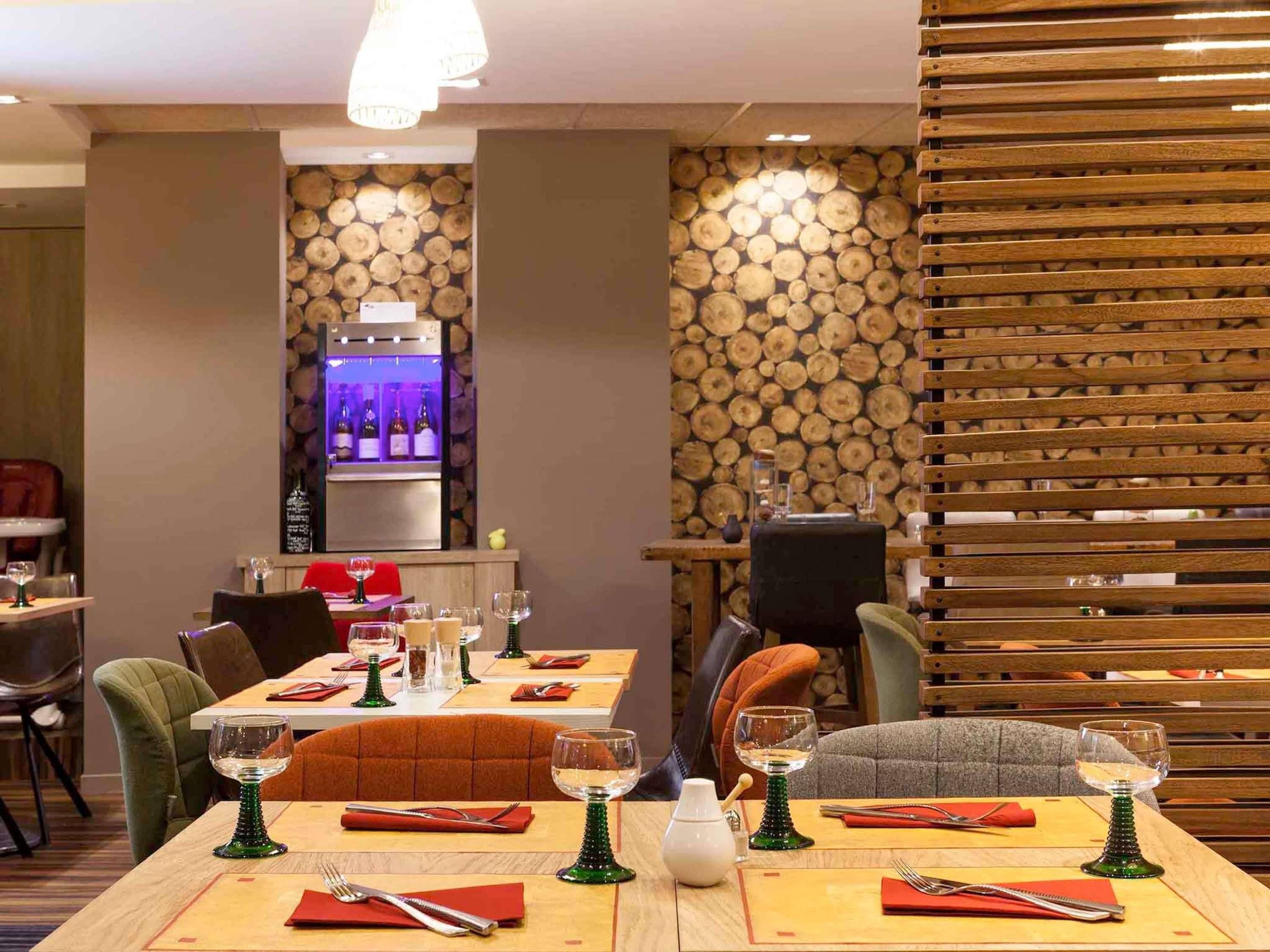 A restaurant interior with wooden log walls, tables set for dining, and a wine display.