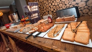 A buffet table with various breads and pastries, a toaster, and a bottle of apple juice.