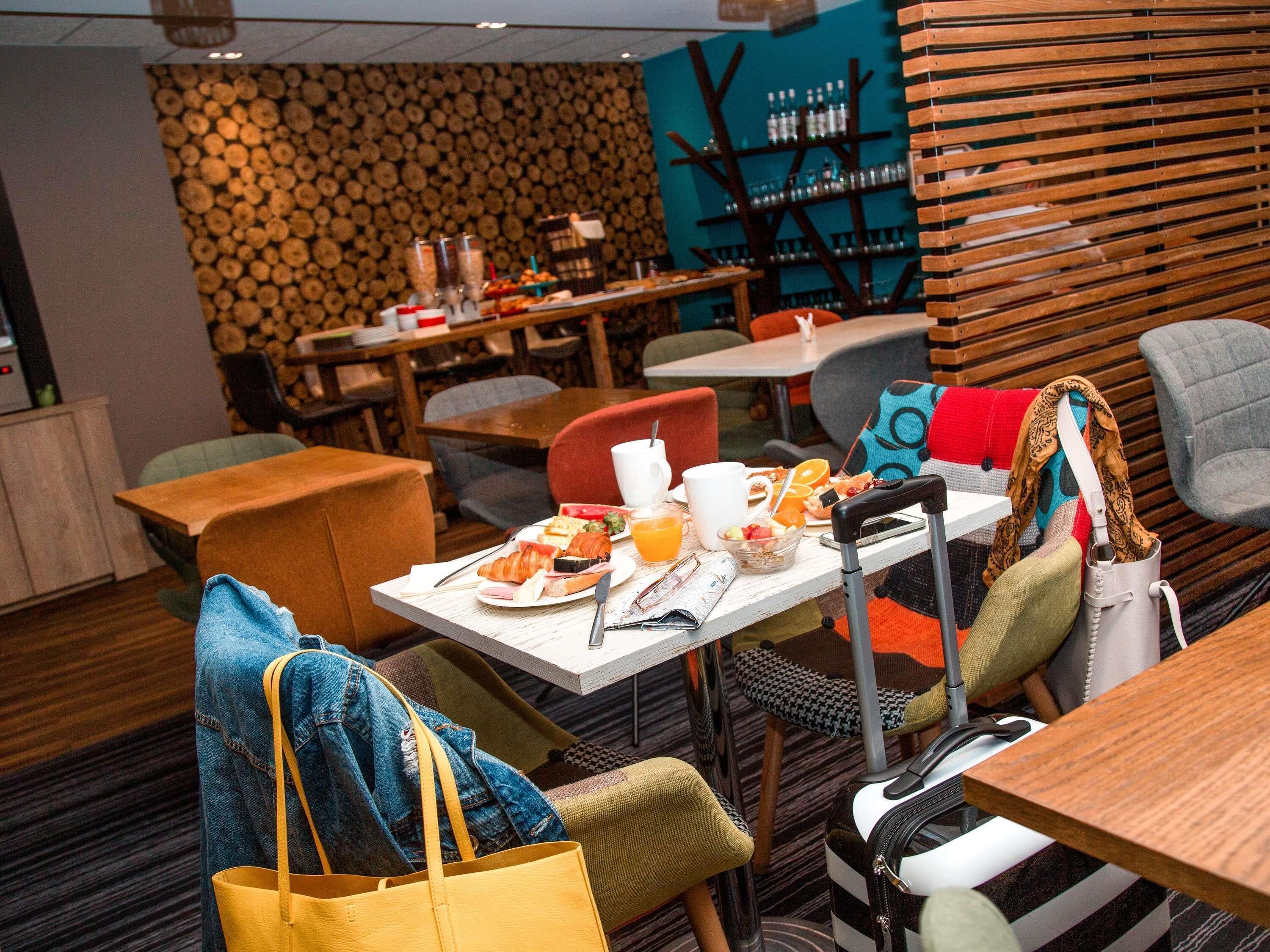 A restaurant with wooden wall decor, tables with breakfast items, and a variety of seating options.