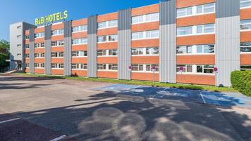 A B&B hotel with a modern brick facade, multiple windows, and a parking lot with handicapped parking spaces.