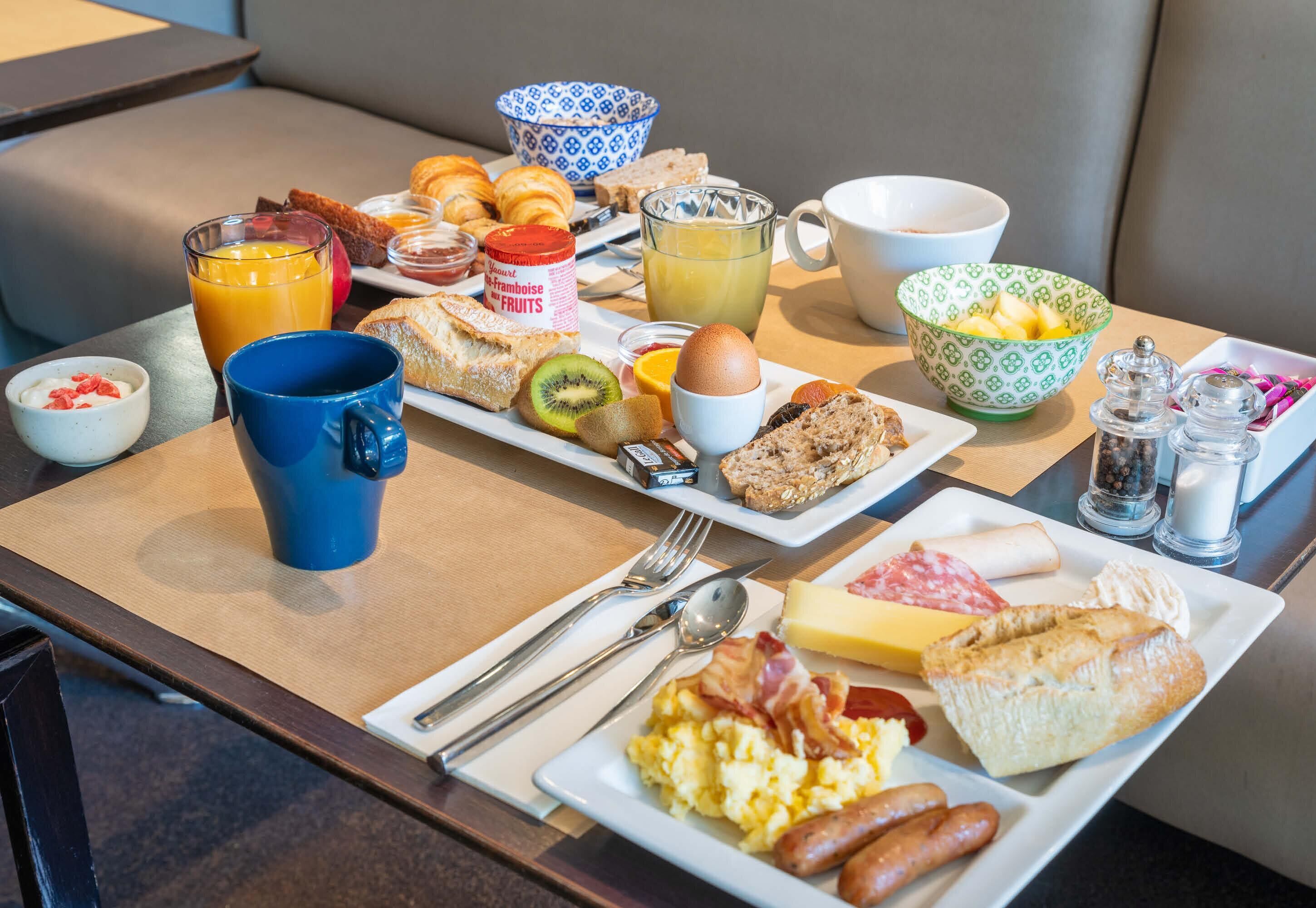 Un buffet de petit-déjeuner proposant une variété d’aliments et de boissons, notamment des croissants, des œufs, des saucisses et un assortiment de fruits.