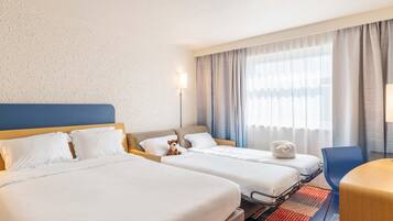 A hotel room with two beds, a desk, a chair, and a large window with curtains.