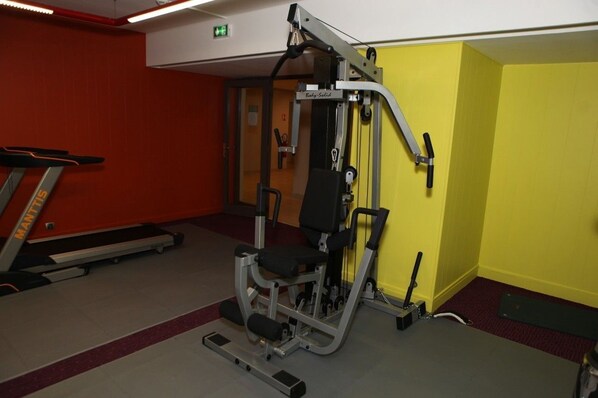 A gym with a treadmill, a weight machine, and a yellow wall.