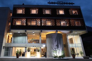 Un hôtel doté d’une façade moderne, de nombreux balcons et d’une entrée imposante agrémentée de plantes en pot.
