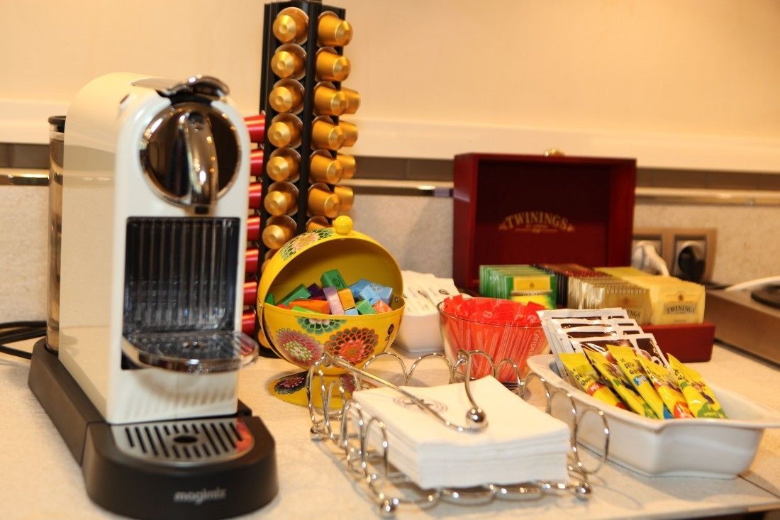 Une machine à café, un bol rempli de fournitures de bureau colorées et un plateau de collations sur un comptoir.