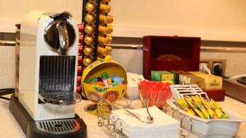 Une machine à café, un bol rempli de fournitures de bureau colorées et un plateau de collations sur un comptoir.