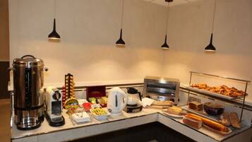 Un mostrador de buffet con diversos alimentos, una máquina de café, un hervidor y un microondas.