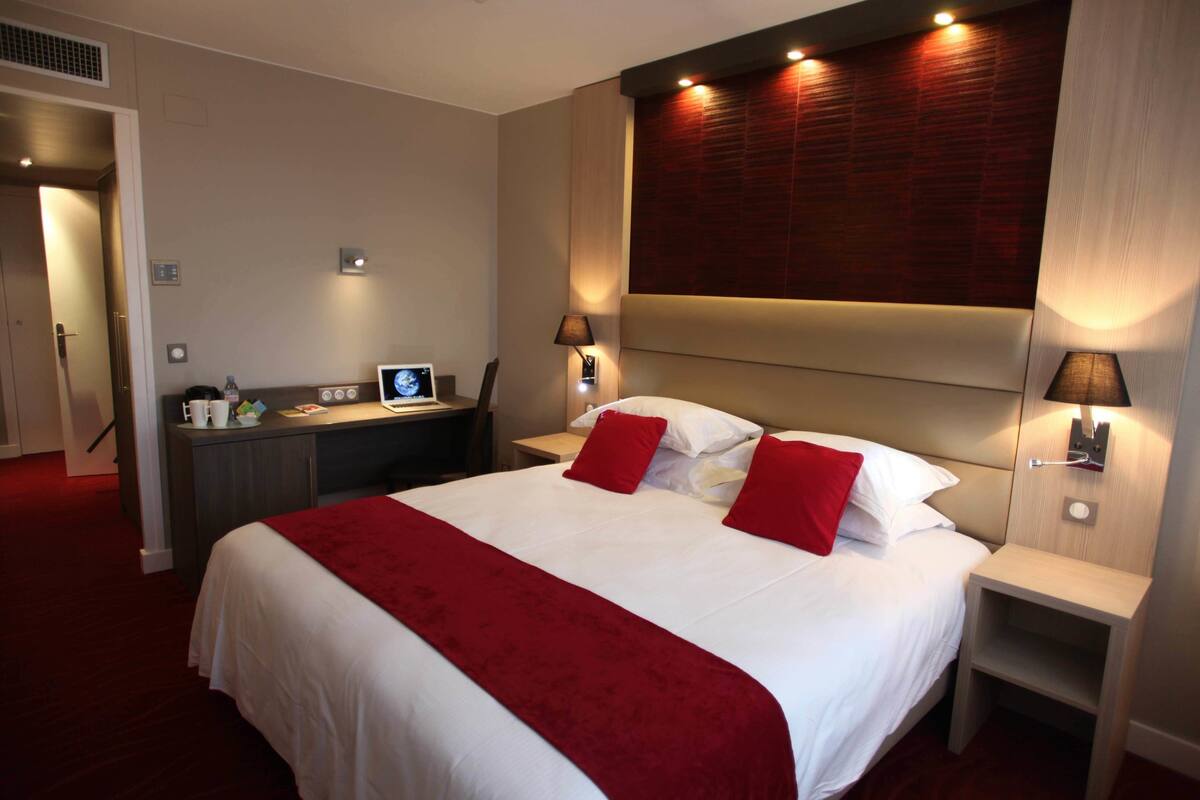 A hotel room with a large bed, a desk, and two bedside tables.