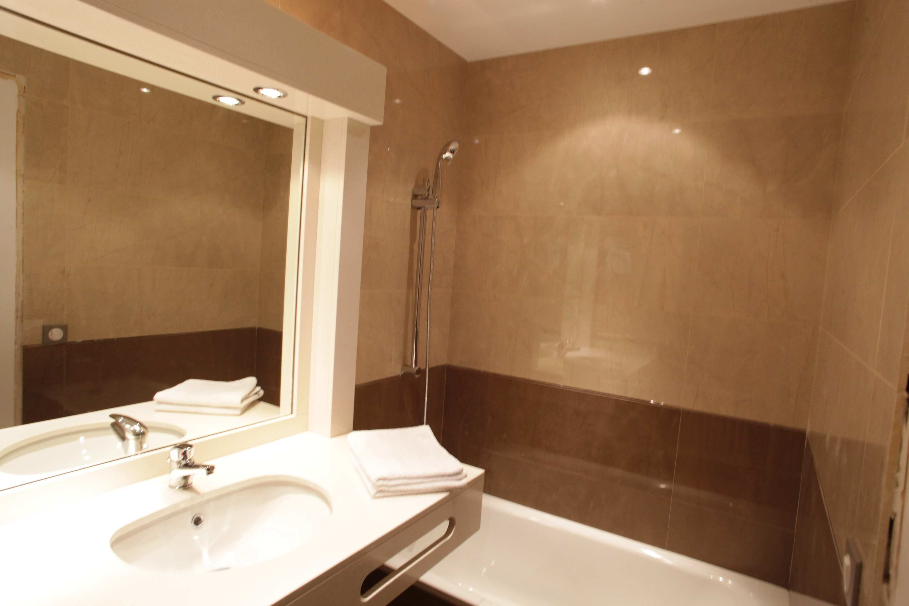 A bathroom with a sink, mirror, and shower.